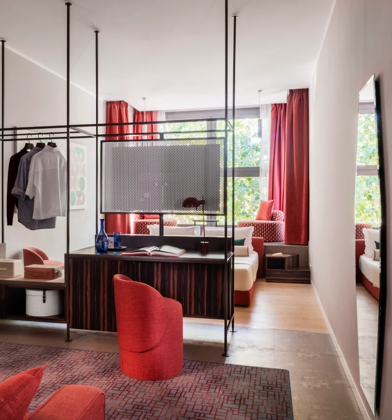 Zona living della suite con divano rosso, scrittoio e guardaroba aperto - Parioli Cube Hotel, BZAR hotels a Roma